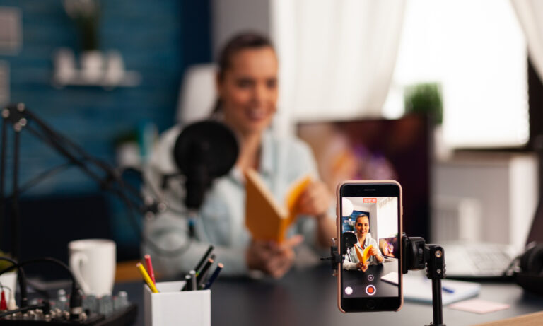 A woman recording a short-form video on her smartphone in a home studio, showcasing content creation for social media marketing.