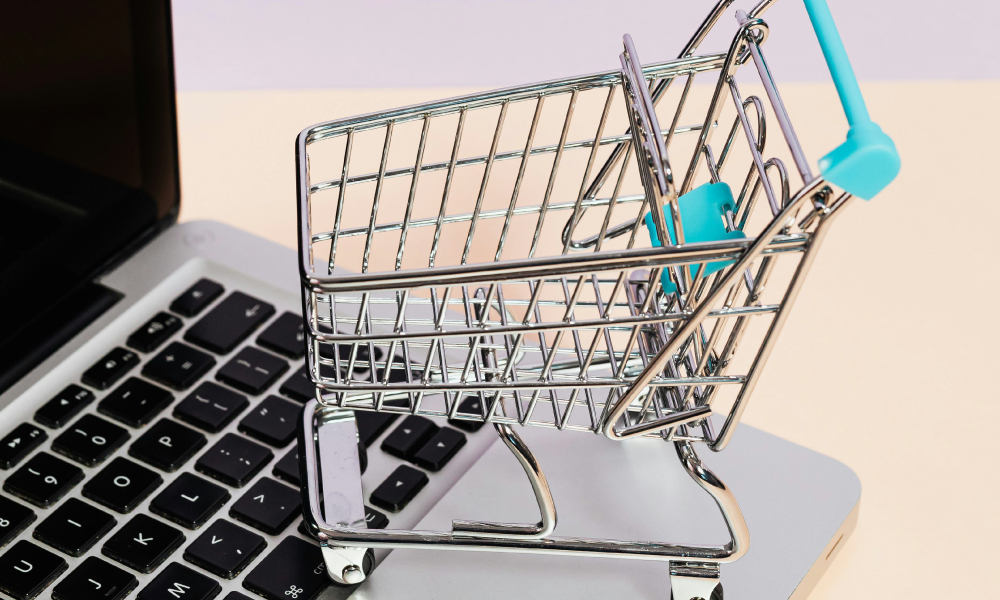 Alt text: **A miniature shopping cart placed on a laptop keyboard, symbolizing the rise of social commerce and the integration of online shopping with digital platforms.**